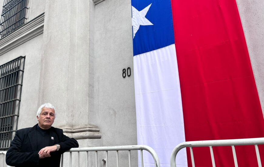 Diputado Hernán Palma en la puerta de Morandé 80 con una bandera chilena.